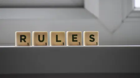Het woord 'Rules' gespeld met Scrabble-achtige stenen op een lichte achtergrond.