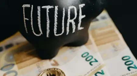 Zwart spaarvarken met het woord 'Future' erop, omringd door eurobiljetten en Bitcoin-munten.